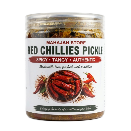 Whole stuffed red chilli pickle soaked in mustard oil inside a glass jar.